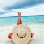Kobieta w kapeluszu wypoczywająca na plaży.