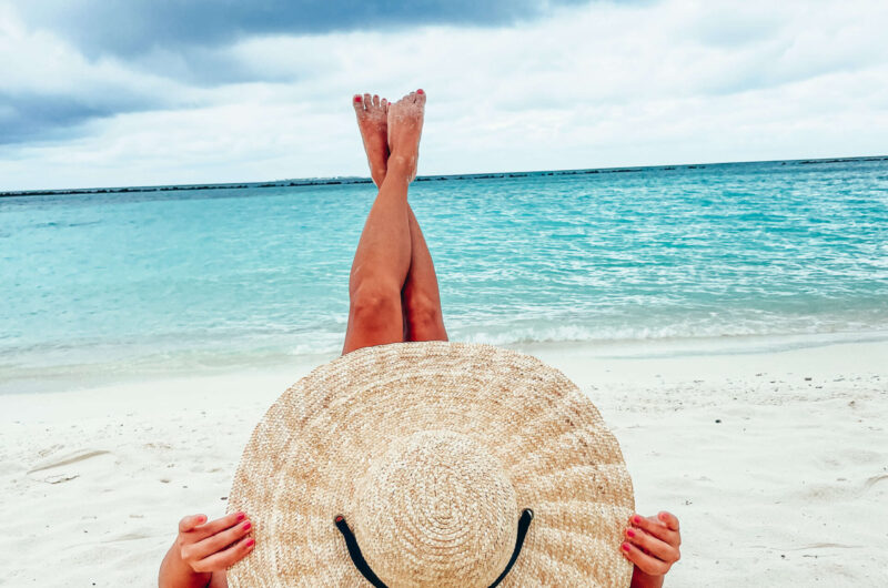 Kobieta w kapeluszu wypoczywająca na plaży.